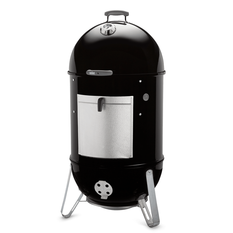 Angled view of the black Weber 22" Smokey Mountain Cooker Smoker with a lid thermometer, aluminum fuel door, silicone temperature grommet, and three metal legs.