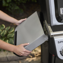 Close-up of a person folding down the left side table on the Weber Spirit E-325 Gas Grill.