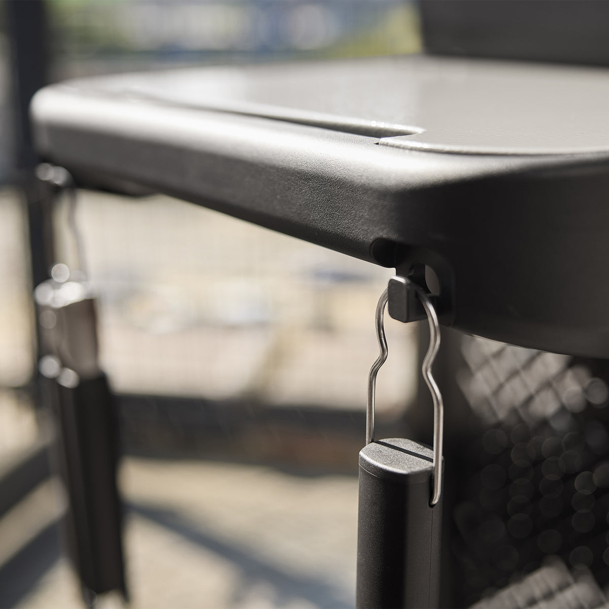 Close-up of grilling tools hanging from hooks beneath the Weber Spirit E-210 Gas Grill’s side table.