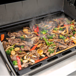 Weber Rust-Resistant Griddle Insert turns a compatible grill into a flat-top cooking surface for beef and vegetable stir-fry.