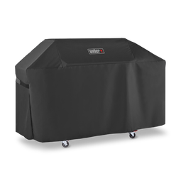A fastening strap on the left side holds the black Weber Premium Grill Cover around a Genesis grill, with fitted seams outlining the lid and side tables.