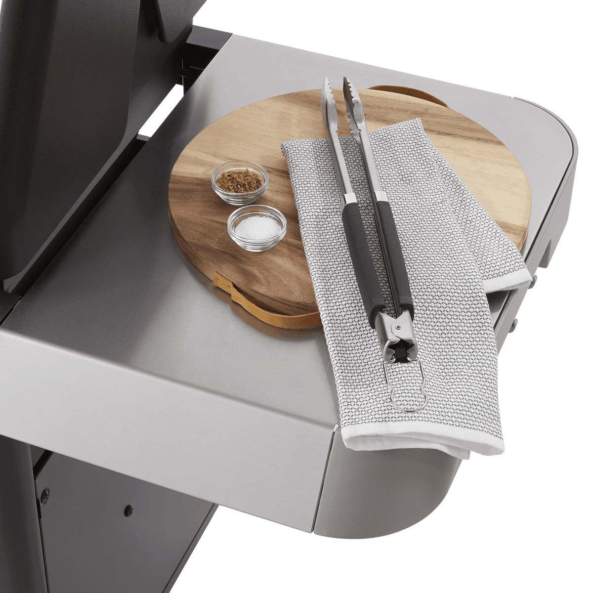 Extra-large prep and serve table keeps a cutting board, seasonings, and tongs within reach.